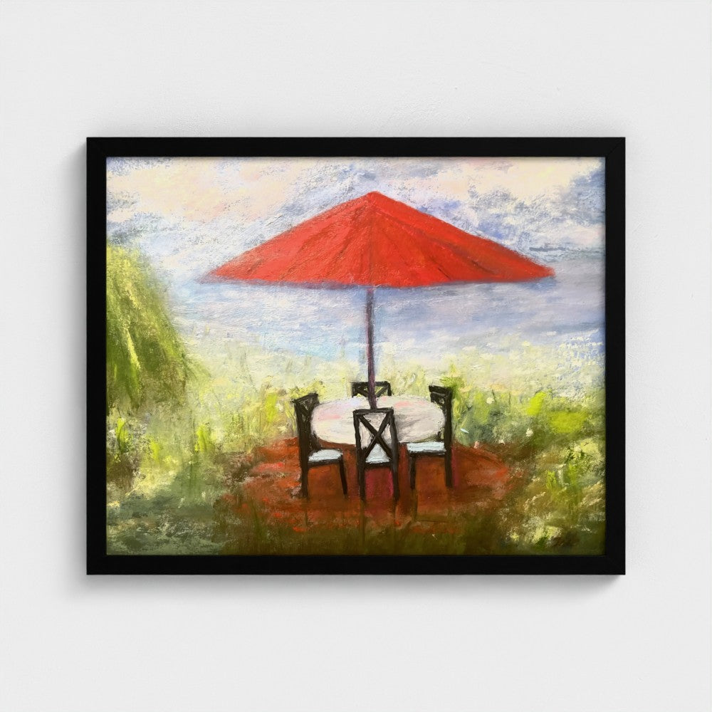 Framed impressionistic painting of an outdoor setting with a red umbrella, table, and chairs.