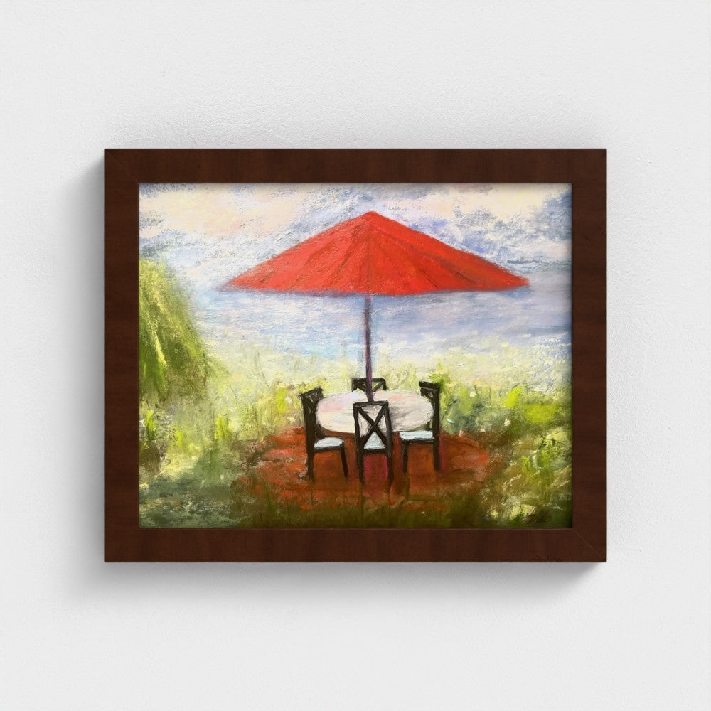 Framed impressionistic painting of an outdoor setting with a red umbrella, table, and chairs.