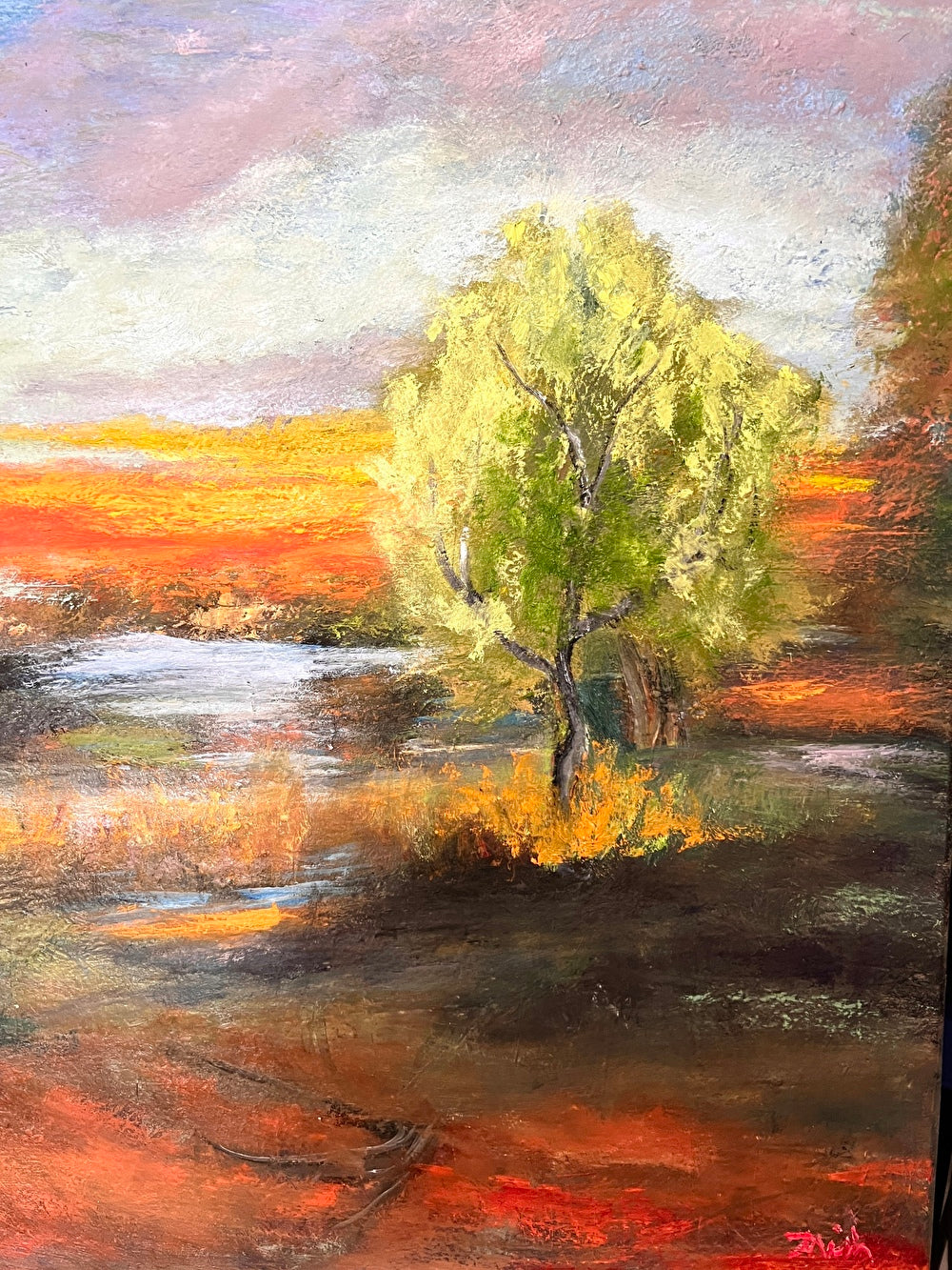 Impressionist painting of a bright green spring tree with golden sunset light over land and water
